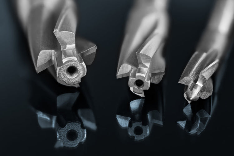 Three drill bits laid on a reflective surface